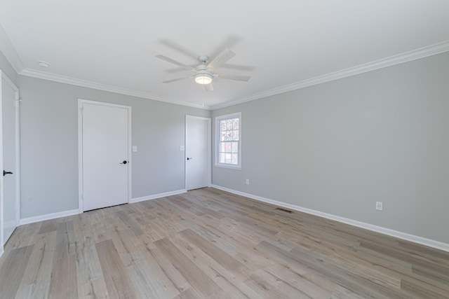 spare room with crown molding, visible vents, light wood-style floors, a ceiling fan, and baseboards