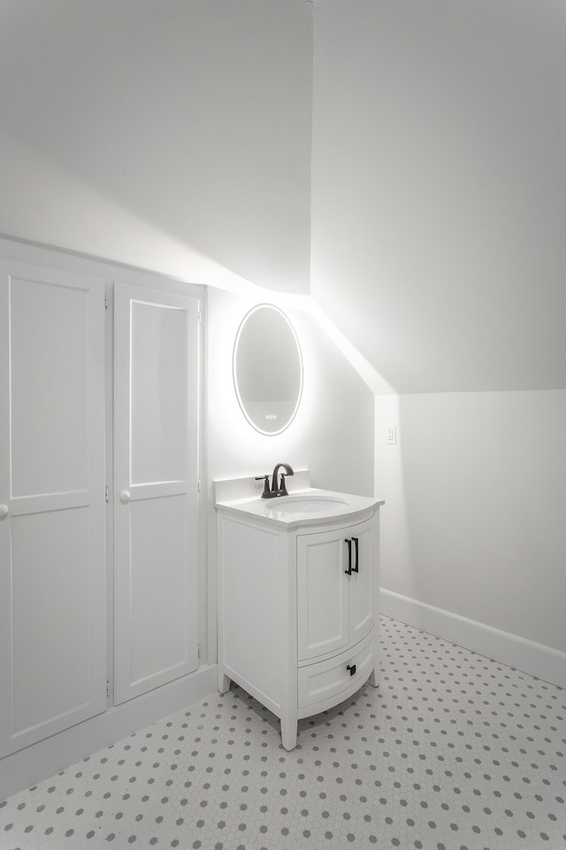 bathroom featuring lofted ceiling, vanity, baseboards, and tile patterned floors