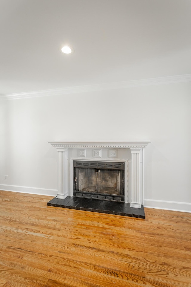 room details featuring crown molding, a fireplace, baseboards, and wood finished floors