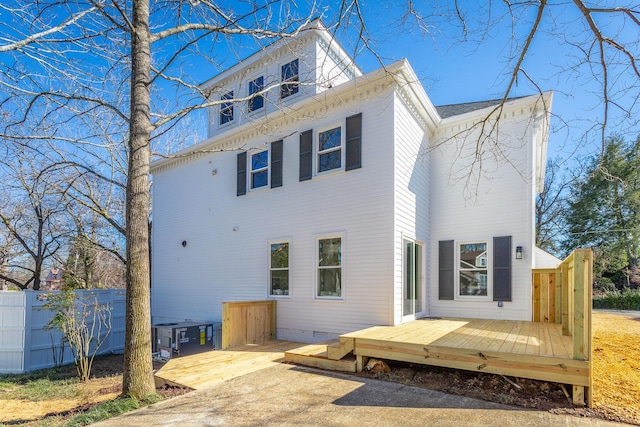 rear view of house with crawl space, a wooden deck, and fence