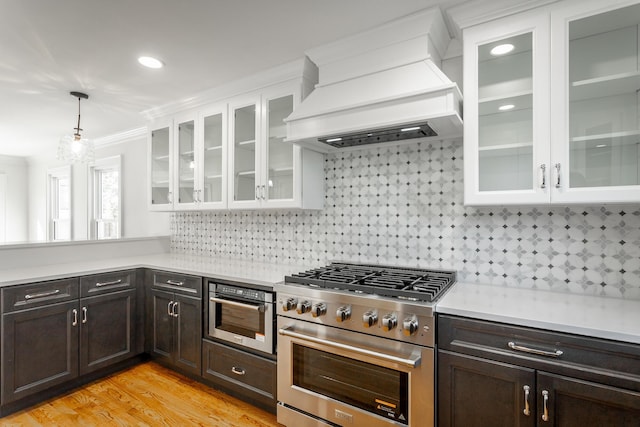 kitchen featuring stainless steel appliances, glass insert cabinets, and light countertops