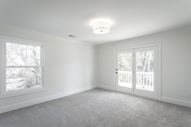 empty room featuring carpet floors, visible vents, crown molding, and baseboards