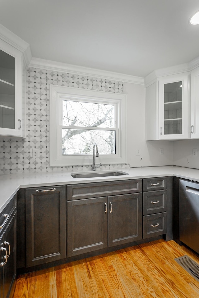 kitchen with light countertops, a sink, and glass insert cabinets