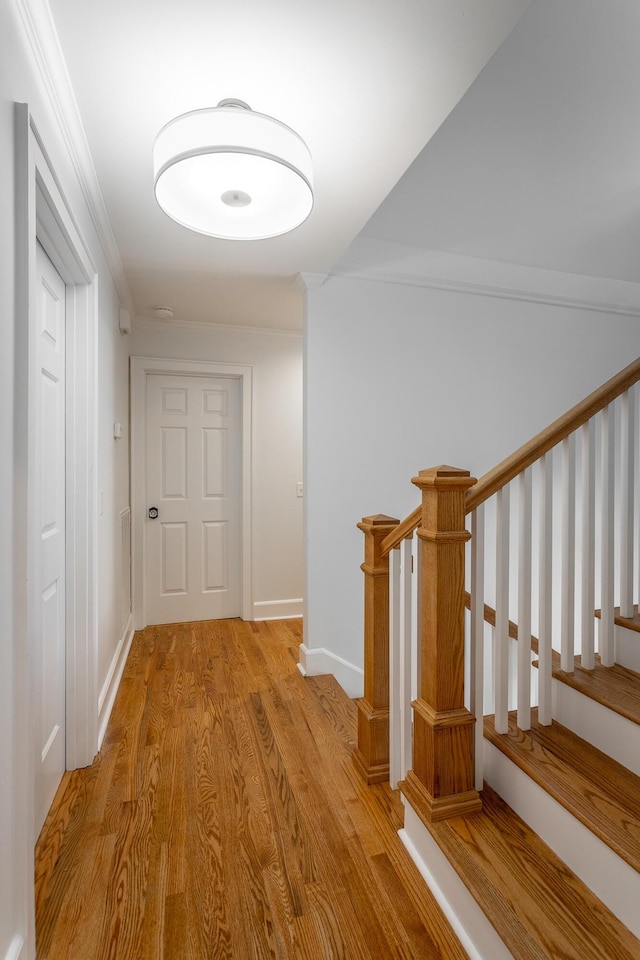 corridor with stairs, light wood finished floors, and baseboards