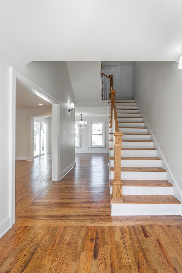 staircase with baseboards, wood finished floors, and a healthy amount of sunlight