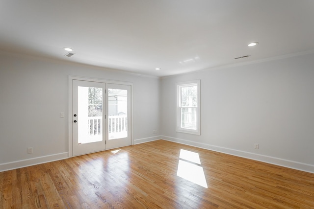 unfurnished room featuring light wood finished floors, visible vents, and crown molding