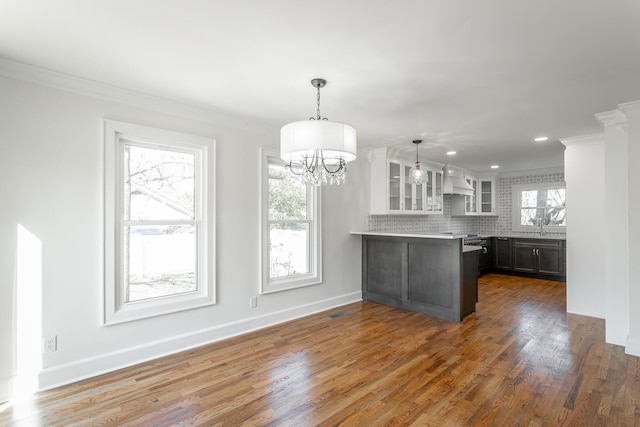 kitchen with a peninsula, white cabinets, light countertops, custom exhaust hood, and glass insert cabinets