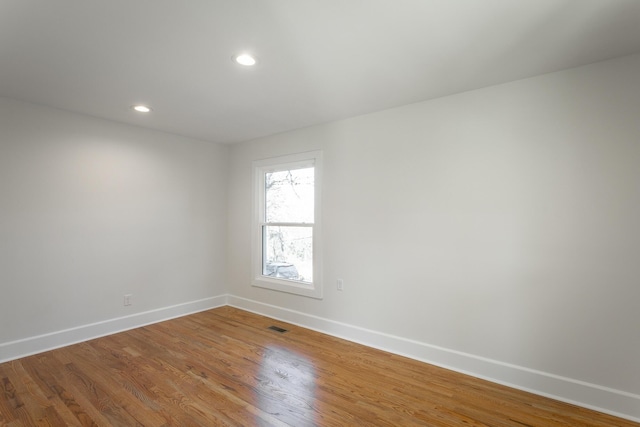 unfurnished room featuring recessed lighting, wood finished floors, visible vents, and baseboards