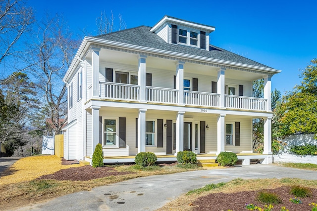 view of front of home with a shingled roof, covered porch, and a balcony