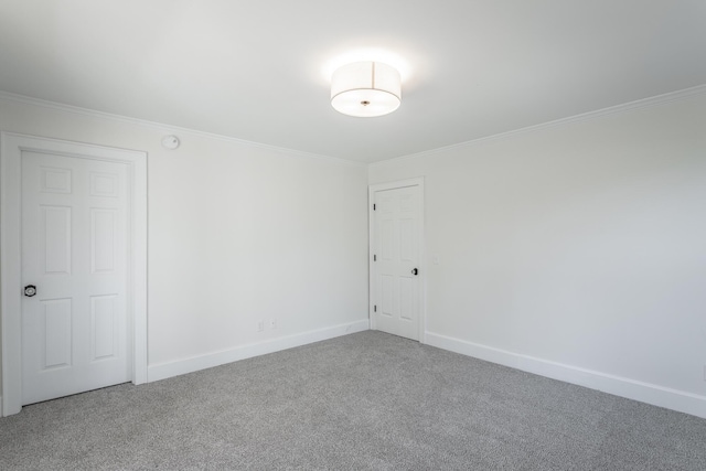 carpeted empty room with ornamental molding and baseboards