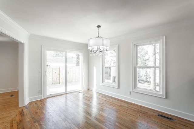 unfurnished dining area with crown molding, visible vents, a chandelier, and wood finished floors