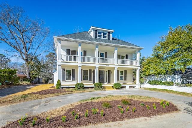 view of front facade featuring driveway, covered porch, and a balcony