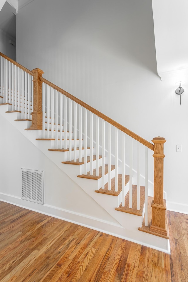 stairs with visible vents, baseboards, and wood finished floors