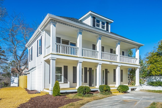 neoclassical home featuring a porch and a balcony