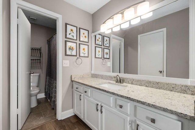 full bath featuring toilet, wood finished floors, vanity, visible vents, and baseboards