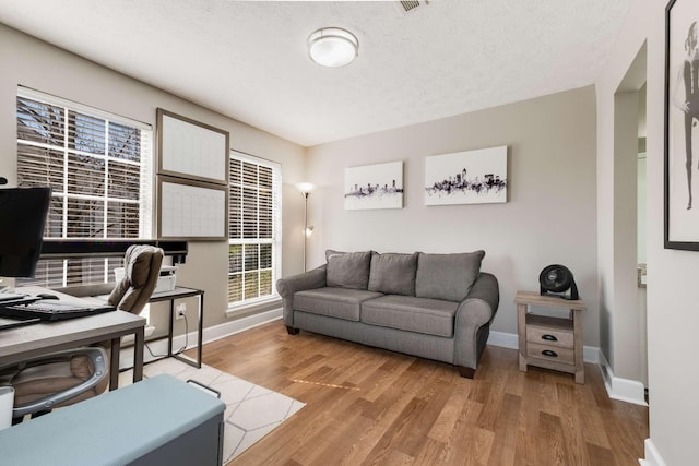 office space with light wood-style floors, baseboards, and a textured ceiling