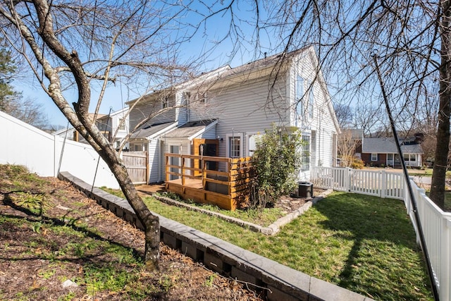 rear view of property with a fenced backyard, a wooden deck, and a yard