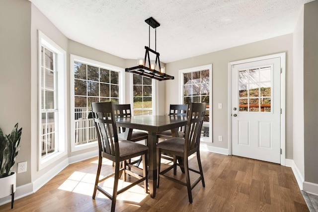 dining room with a chandelier, a textured ceiling, baseboards, and wood finished floors