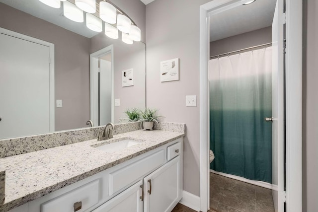 bathroom featuring baseboards, vanity, and toilet