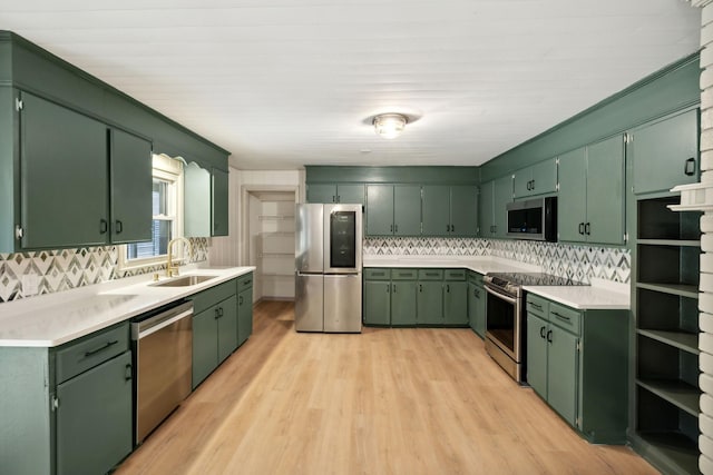 kitchen featuring appliances with stainless steel finishes, light countertops, a sink, and green cabinets