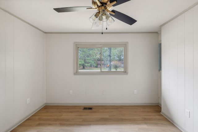 spare room featuring visible vents, crown molding, light wood-style flooring, and baseboards