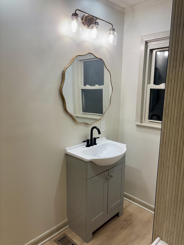 bathroom with visible vents, vanity, baseboards, and wood finished floors