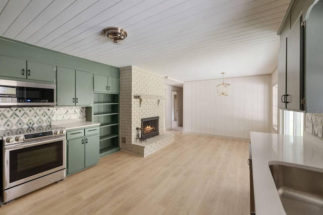 kitchen featuring green cabinets, light countertops, appliances with stainless steel finishes, and hanging light fixtures