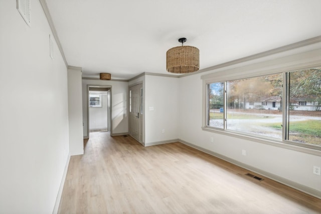 interior space featuring crown molding, baseboards, visible vents, and light wood-style floors