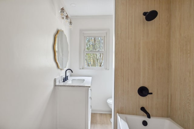 bathroom featuring baseboards, toilet, wood finished floors, vanity, and shower / bathing tub combination