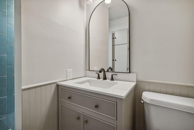 bathroom with a wainscoted wall, vanity, and toilet