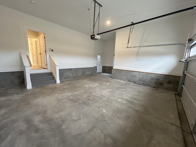 garage featuring concrete block wall and a garage door opener