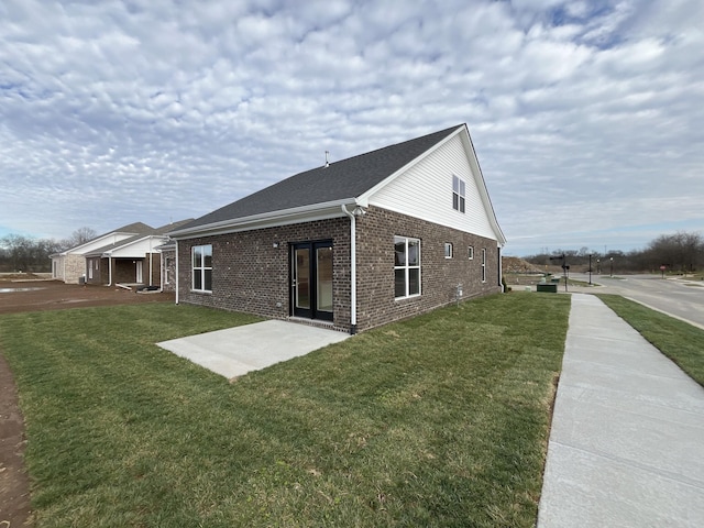 exterior space with a yard, a patio, and brick siding