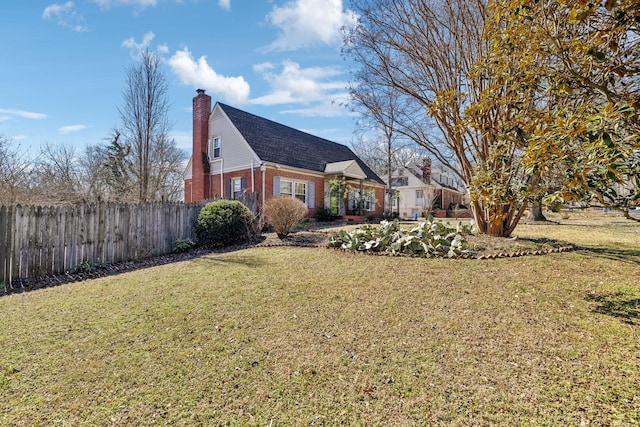 view of home's exterior featuring a chimney, fence, a lawn, and brick siding