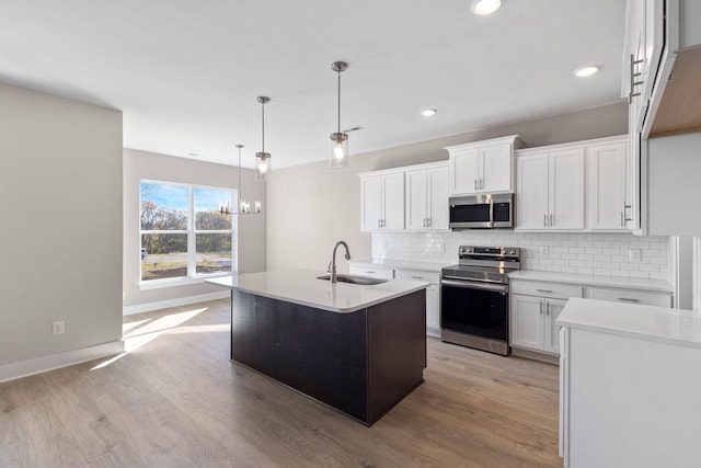 kitchen featuring tasteful backsplash, white cabinets, light wood-style flooring, appliances with stainless steel finishes, and a sink