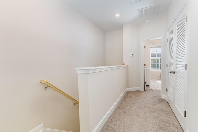 corridor featuring light carpet, attic access, visible vents, baseboards, and an upstairs landing