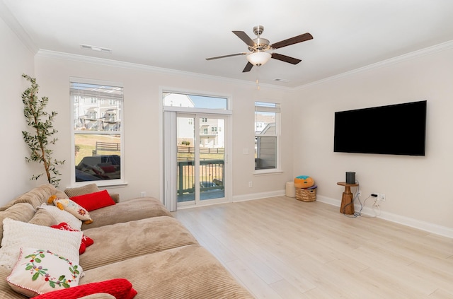 living room featuring a healthy amount of sunlight, light wood-style flooring, baseboards, and crown molding