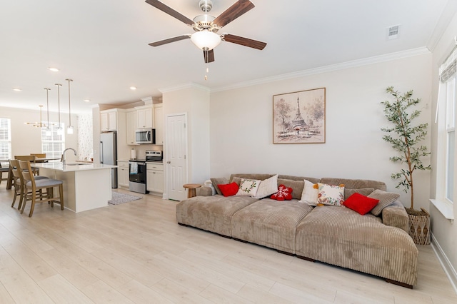 living room with baseboards, visible vents, ceiling fan, crown molding, and light wood-type flooring