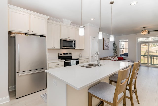 kitchen with stainless steel appliances, white cabinets, a sink, and a center island with sink