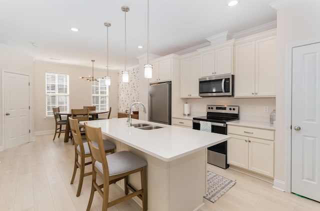 kitchen featuring stainless steel appliances, a center island with sink, a sink, and light countertops