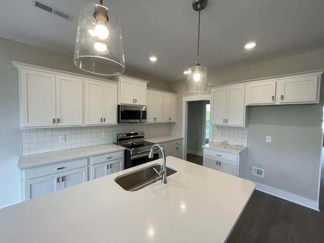 kitchen featuring appliances with stainless steel finishes, white cabinets, light countertops, and decorative light fixtures