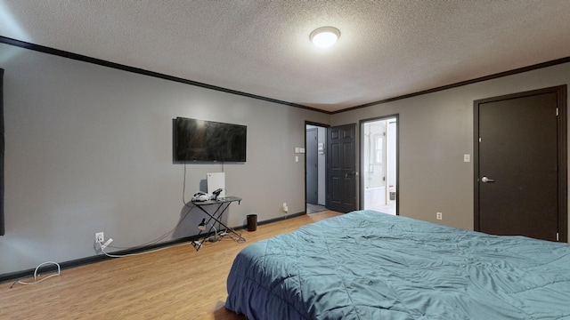 bedroom featuring baseboards, connected bathroom, ornamental molding, wood finished floors, and a textured ceiling