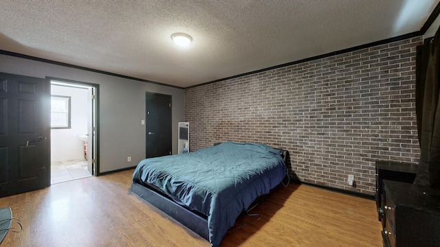 bedroom with ornamental molding, brick wall, and wood finished floors