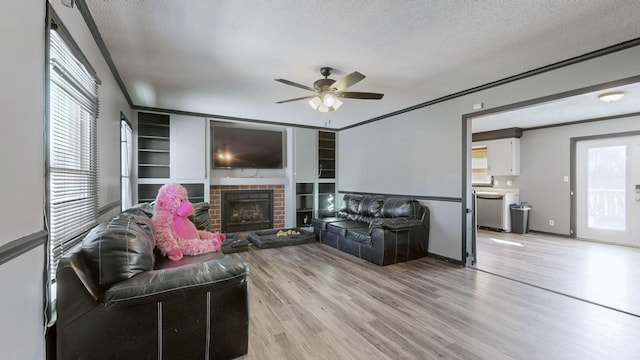 living room featuring a textured ceiling, light wood-type flooring, a fireplace, and crown molding