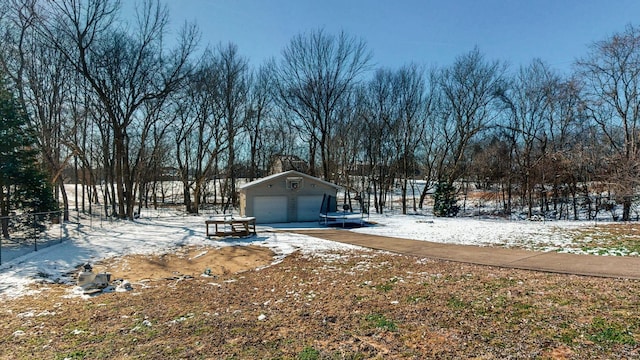 snowy yard with an outbuilding and a detached garage