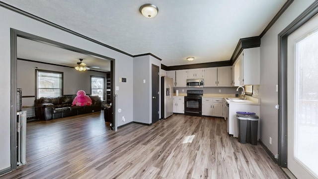 kitchen with a sink, white cabinets, open floor plan, light countertops, and appliances with stainless steel finishes