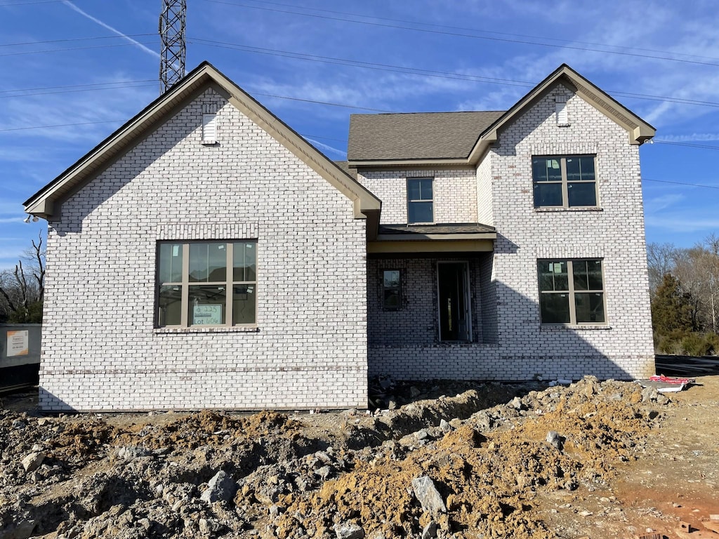 view of front facade with a shingled roof and brick siding