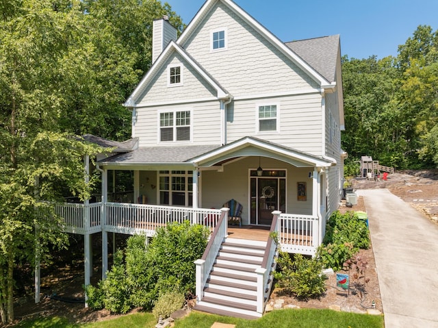 view of front of home featuring covered porch, stairs, a chimney, and a shingled roof