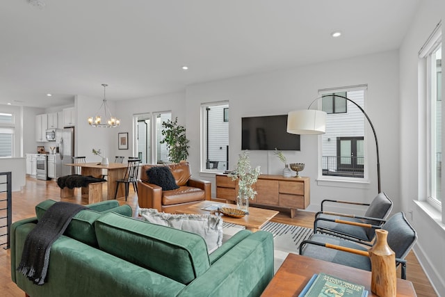 living area featuring a chandelier, recessed lighting, light wood-type flooring, and baseboards