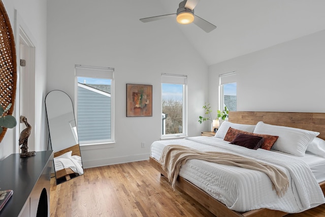 bedroom with light wood-style floors, high vaulted ceiling, baseboards, and a ceiling fan