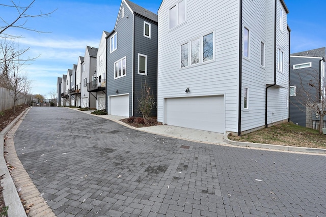 view of side of property featuring driveway, a garage, and a residential view